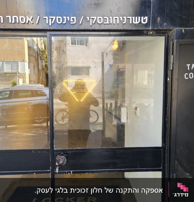 דלת זכוכית עם השתקפות אדם ושלט ניאון